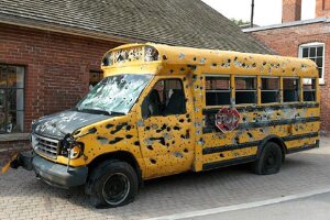 art installation, mini-school bus shot full of bullet holes.